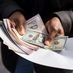 Mains tenant formulaires et billets de banque etales