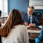 Notaire assis a son bureau face a famille hesitante silencieuse