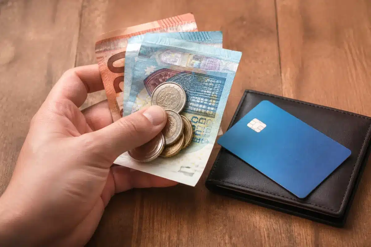 Billets et pieces en main pres de carte bancaire
