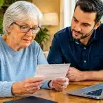 Personne agee tenant document bancaire face a adulte assis pres d'elle