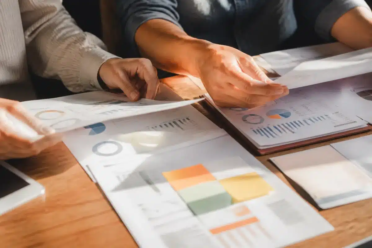 Deux mains triant des documents financiers ensemble à table