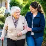 Personne agee assistee par un aidant tenant son bras pour marcher
