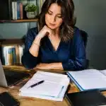 Documents bancaires et testament posés sur bureau devant personne assise