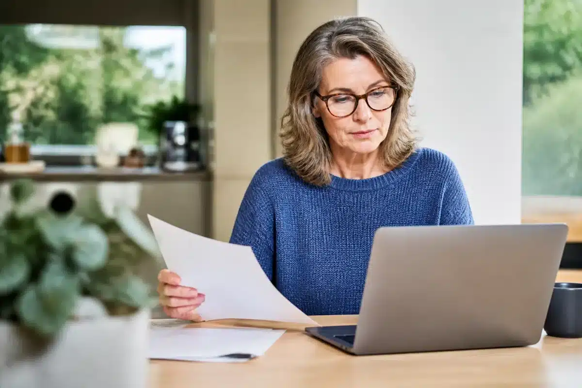 Femme consultant document retraite écran ordinateur portable