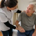 Auxiliaire de vie aidant un vieil homme assis