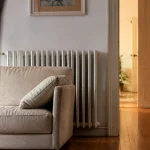 Canape pose devant radiateur, porte ouverte sur couloir