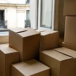 Cartons empiles au sol devant une fenetre ouverte
