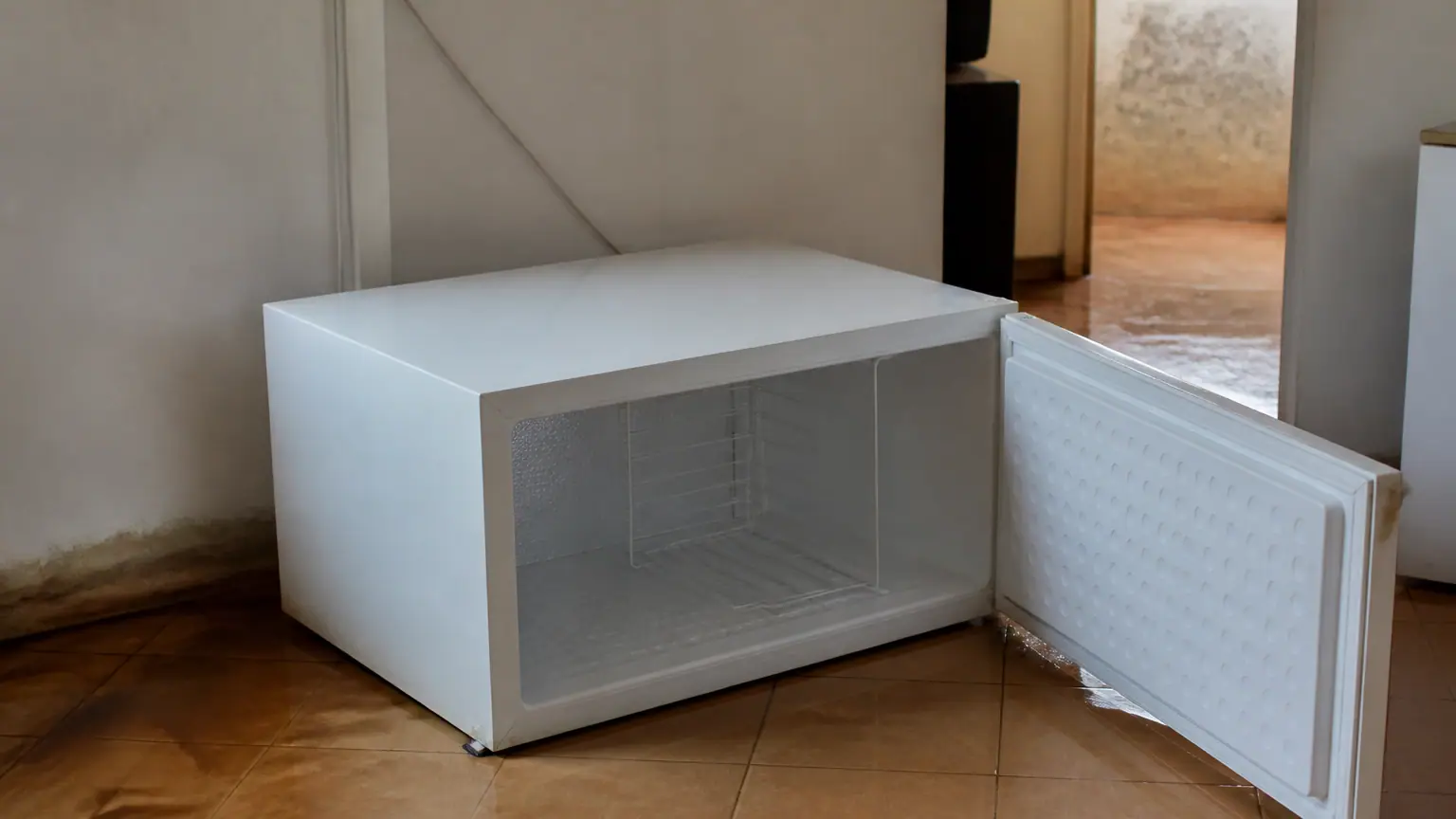Congelateur couche sur carrelage inonde portes ouvertes