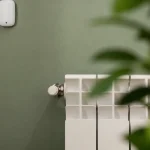 Petit detecteur blanc fixe au mur pres du radiateur