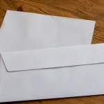 Enveloppe blanche et facture posees sur table en bois