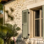 Facade de maison avec persiennes relevees au soleil matinal