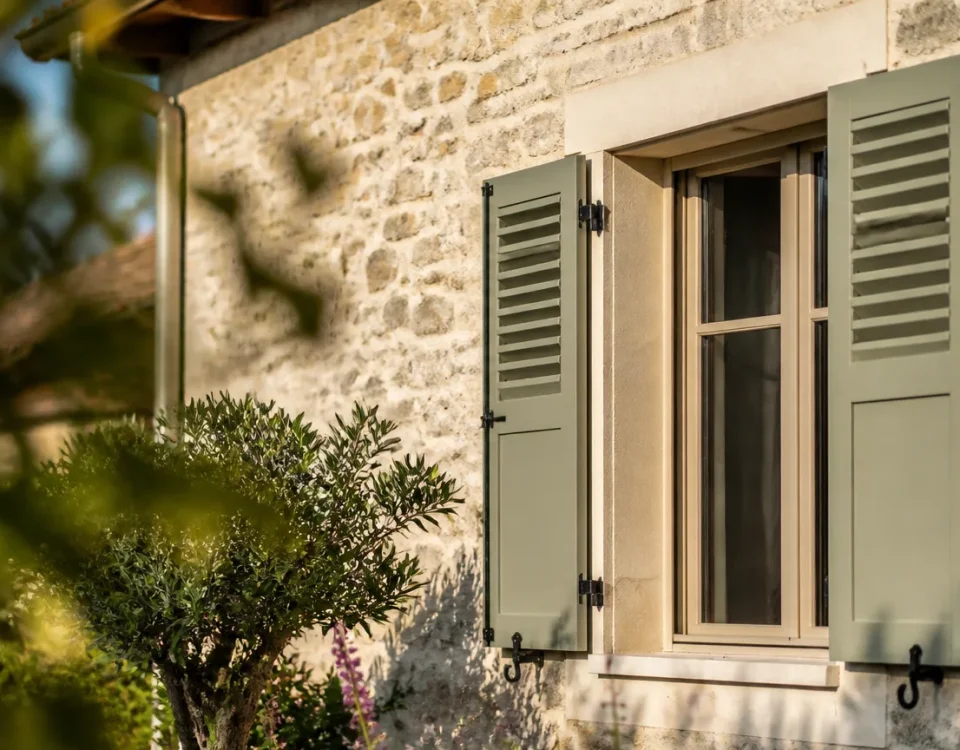 Facade de maison avec persiennes relevees au soleil matinal