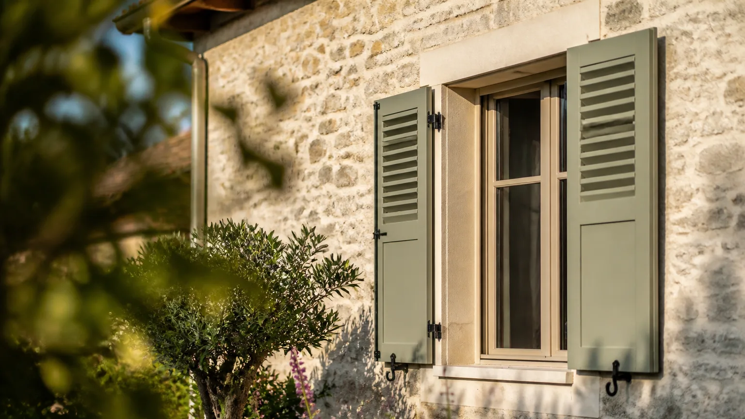 Facade de maison avec persiennes relevees au soleil matinal