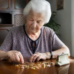 Femme agee assise comptant des pieces sur une table