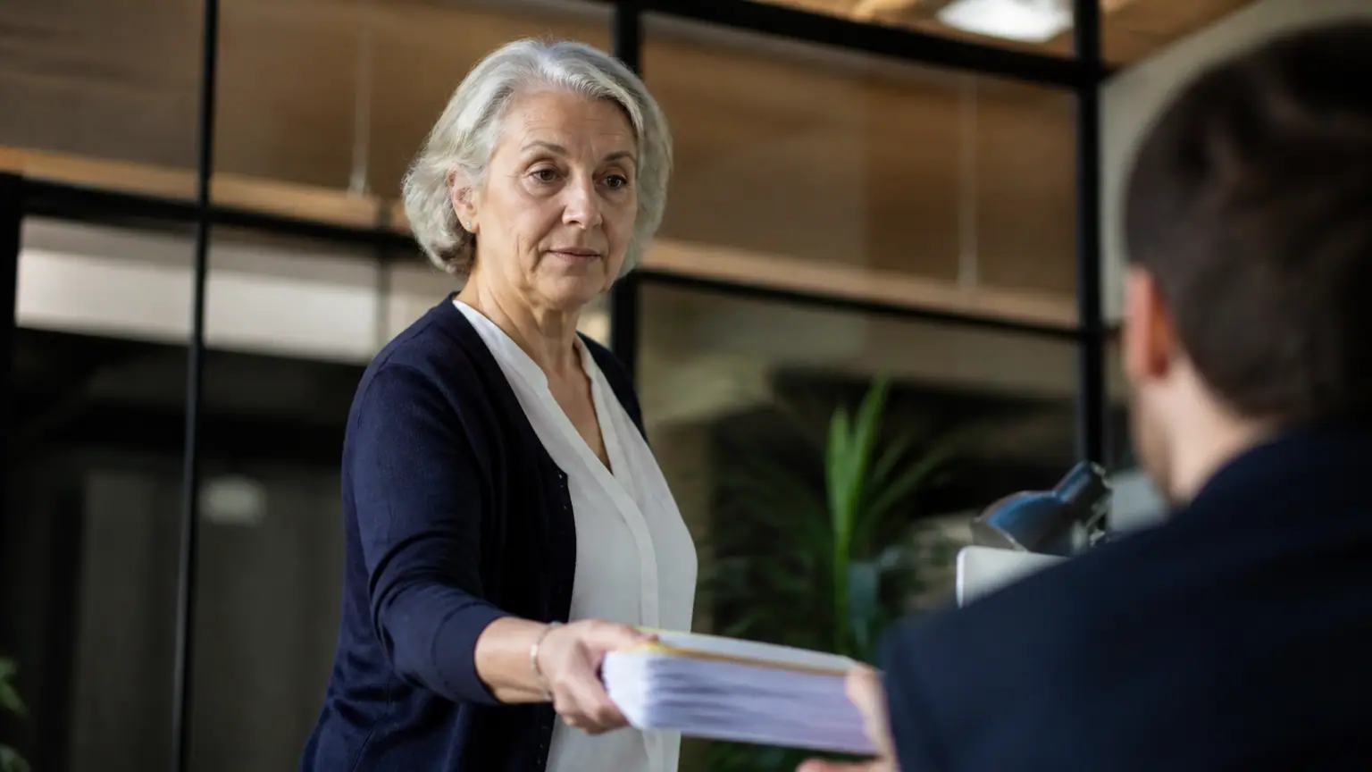 Femme agee debout tendant un dossier a un collegue