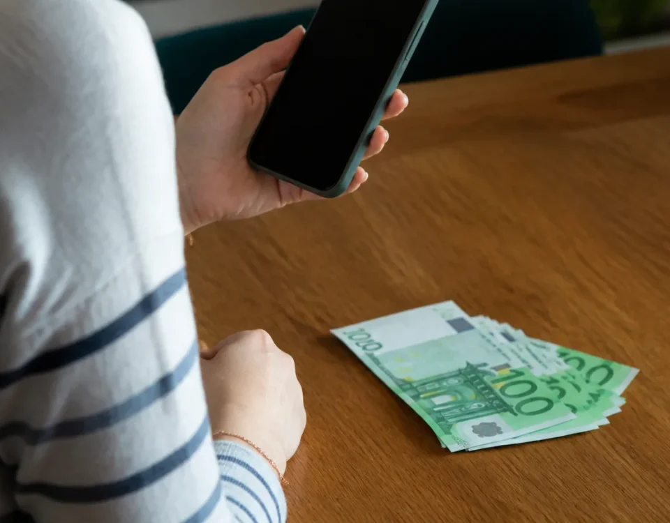 Femme assise tenant smartphone pres de billets 100 euros