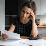 Femme assise a une table avec factures et calculatrice