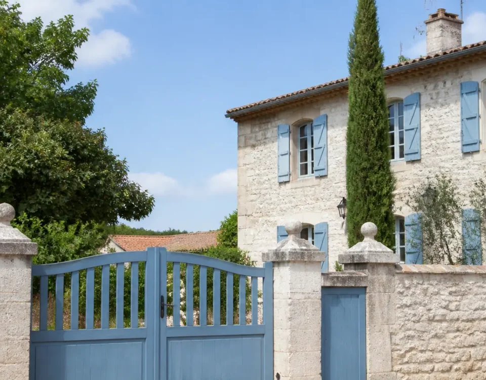 Grande maison en pierre avec volets bleus et portail