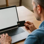 Homme assis devant un ordinateur portable avec carte bancaire