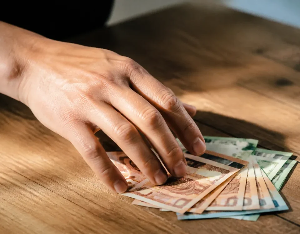 Main tendant des billets sur une table en bois