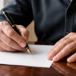 Main ecrivant un testament au stylo plume sur papier