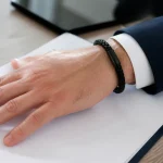 Poignet portant un bracelet noir pose sur un contrat