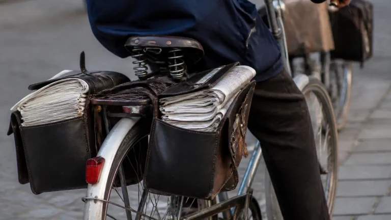 Deux seniors a velo, sacoches pleines de journaux