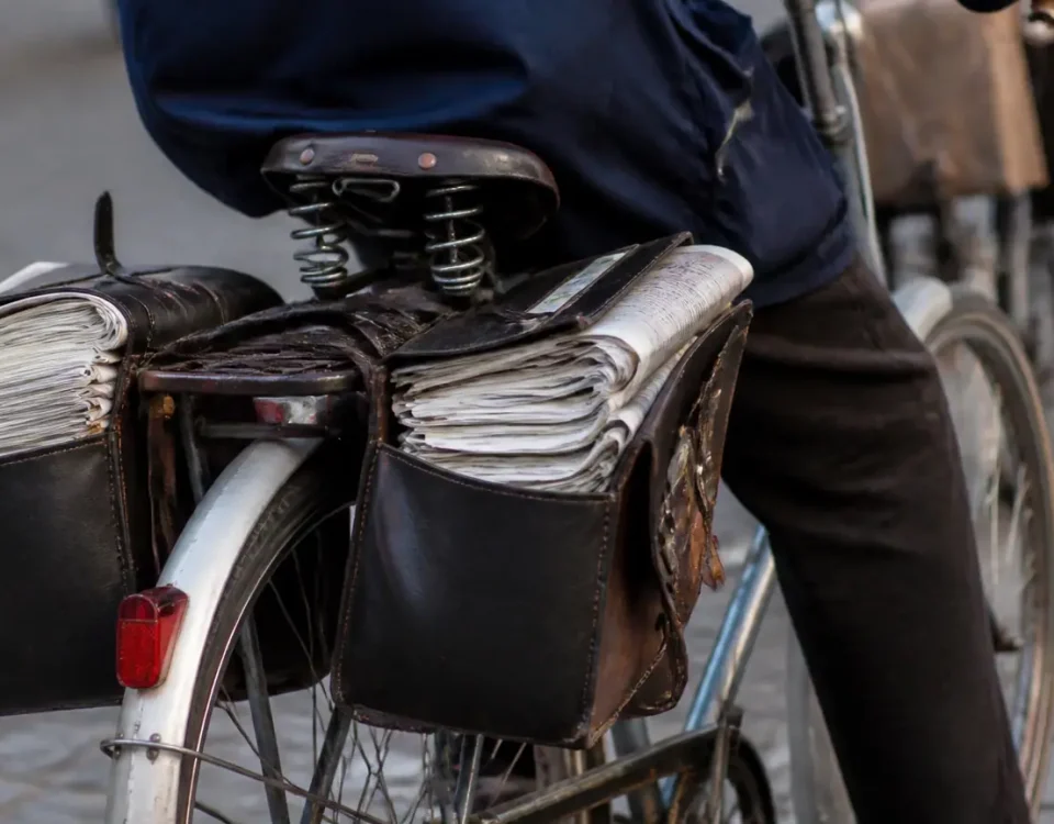 Deux seniors a velo, sacoches pleines de journaux