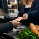 Ticket restaurant tendu a la caisse d'un supermarche