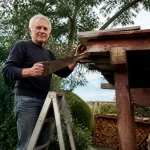 Vieil homme debout sur une echelle tenant une scie