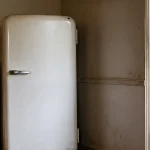 Vieux refrigerateur blanc colle contre un mur de cuisine
